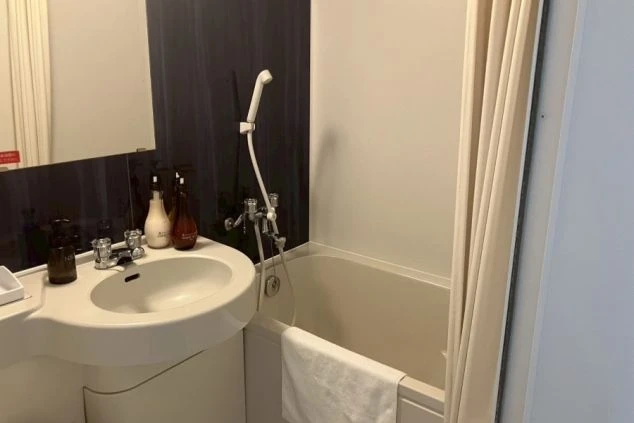 ユニットバス。浴槽とシャワー、そして洗面台がある。洗面台の上にはシャンプーなどのアメニティが置かれている。