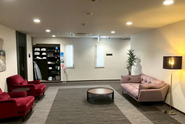 ホテルのロビー。ソファや椅子、丸いテーブルが置かれ、壁にはアートが飾られている。