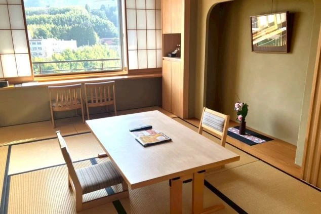 旅館の客室。窓からは緑豊かな自然が見え、非日常の空間が広がっている。