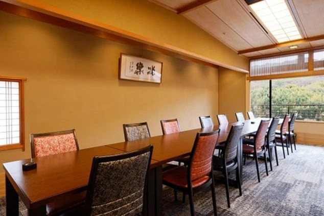旅館の食事処。畳敷きの広間にテーブル席が並び、落ち着いた雰囲気でお客様をお迎えする様子。