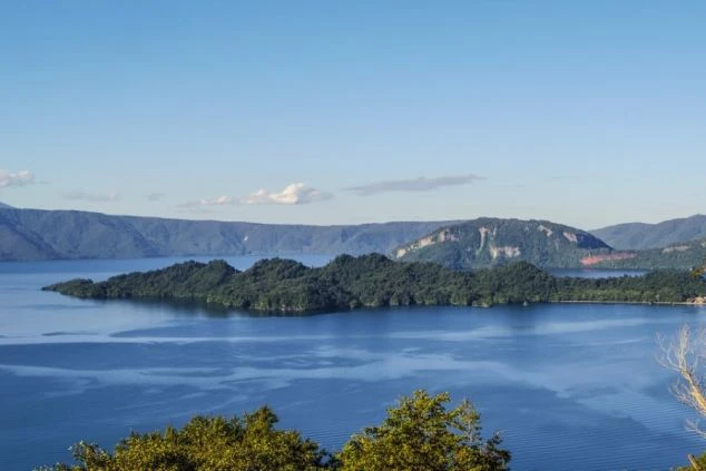 雄大な十和田湖の全景の画像。青い湖面と深い緑の山々が広がり、リゾートバイトで訪れる人々を魅了する美しい景色です。