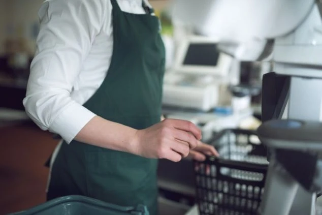 リゾートバイト先のスーパーで、レジ打ちや接客をする店員のイメージ写真。お客様とコミュニケーションをとりながら働ける、リゾートバイトの仕事内容を具体的に伝えます。