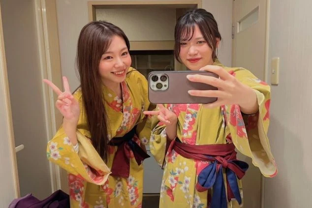 旅館の部屋で、浴衣姿の女性2人が自撮りをしている画像。リゾートバイトの休日に温泉や観光を楽しむイメージ。