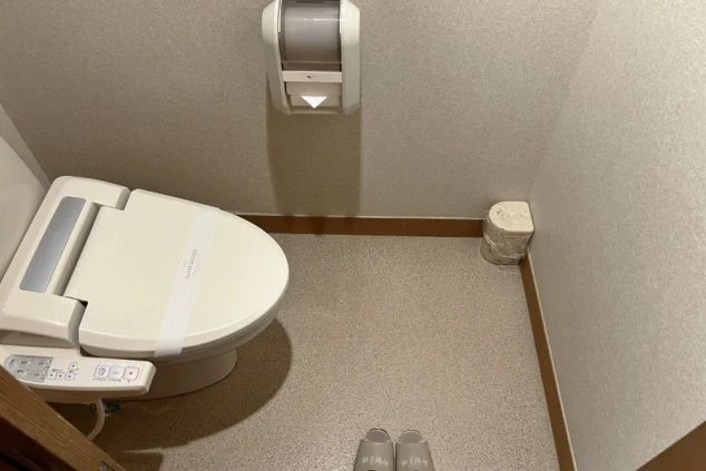 リゾートバイトの寮のトイレの画像。温水洗浄便座付きの洋式トイレが設置され、使い捨てのカバーがされている。