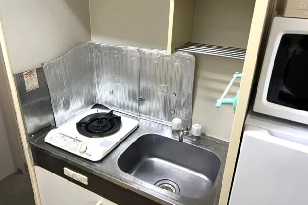 リゾートバイト寮のキッチン。ガスコンロ、シンク、換気扇が見える。簡単な調理が可能。