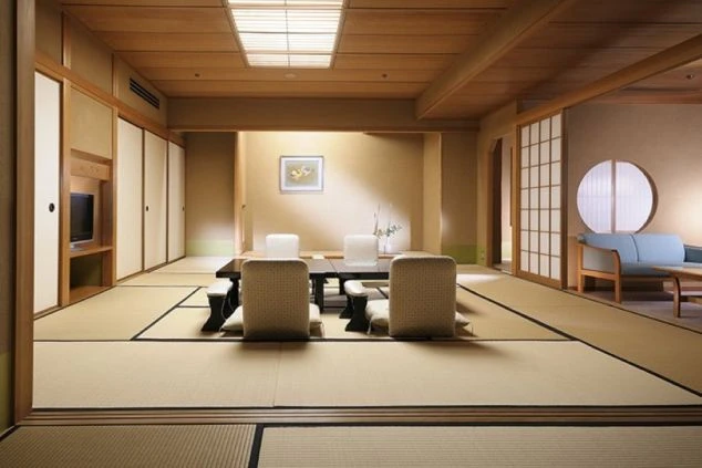 山と森に囲まれた、川向こうに建つベージュ色の水明館の建物群の外観。手前の建物には「北館」の文字が見える。