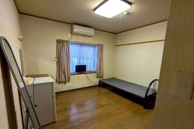 リゾートバイトスタッフ用個室寮の画像。エアコン、テレビ、冷蔵庫、姿見が完備された広々としたフローリングの居室。