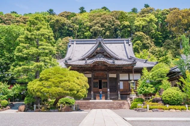 植え込みの中に立つ、旅館またはホテルの黒い看板。