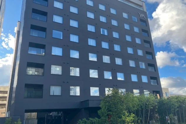 青空を背景に建つ、窓の多い黒いホテルのファサード（正面）。