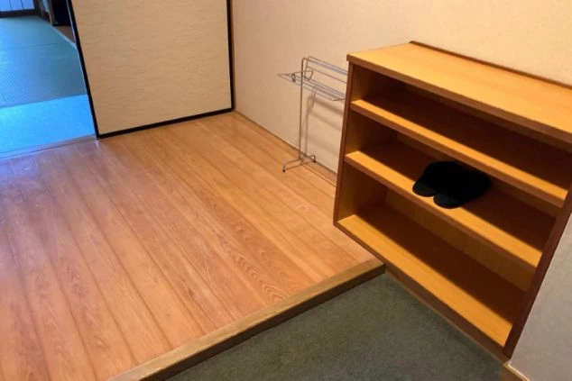 リゾートバイトの客室寮の和室の部屋の画像。黒い座卓と座布団が置かれ、窓際には椅子と小さなテーブルがある。リゾートバイトの寮の部屋の画像。