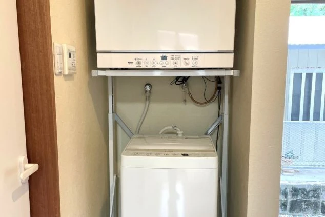 ワクトリの社員が出張で撮影した、リゾートバイトの寮の洗濯機と乾燥機の画像。縦型の洗濯機の上に乾燥機が置かれており、効率的に配置されたランドリースペース。