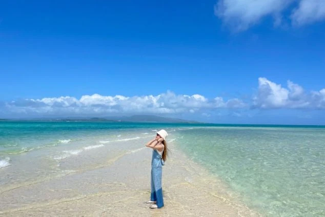 どこまでも続く青い海と白い砂浜に立つ女性。透明度の高い海でのんびり過ごしたり、マリンアクティビティを楽しんだりできる最高のロケーションです。