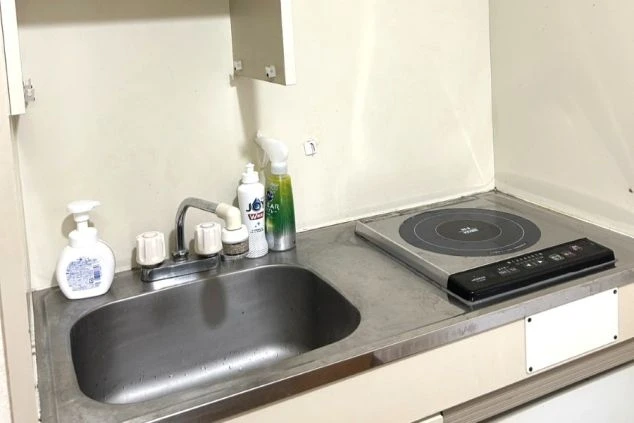 ワクトリの社員が出張で撮影した、リゾートバイトの寮に備え付けられたコンパクトなキッチンの画像。シンクとIHクッキングヒーターがあり、食器用洗剤なども見える。