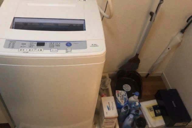 日用品や洗剤とともに置かれた、寮に完備された全自動洗濯機。