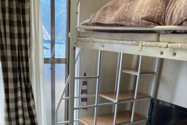 窓から光が差し込む寮のベッドスペース。快適なプライベート空間が確保されており、リラックスして過ごせます。