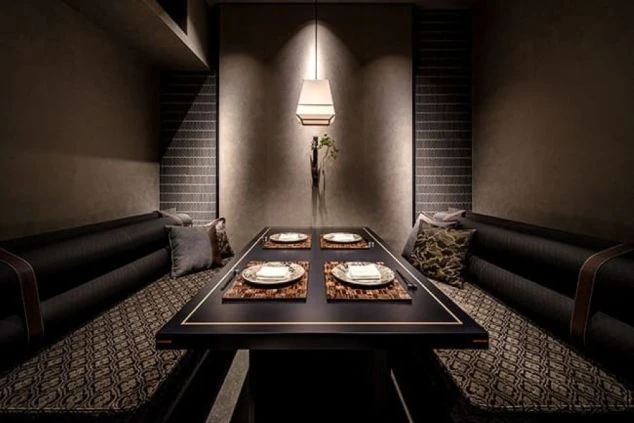 洗練された和モダンの完全個室。中央に置かれた重厚なテーブルを囲むように、柄物のクッションが配されたソファ席が並ぶ。柔らかなペンダントライトが幻想的な空間。