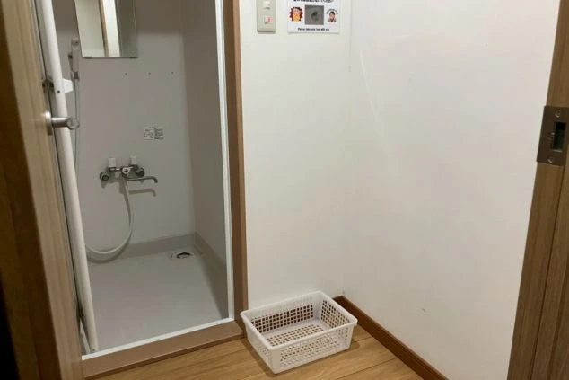 寮の共用トイレ(男性用)。小便器が3つ並び、窓際には換気扇と壁一面のロッカーが設置されている。