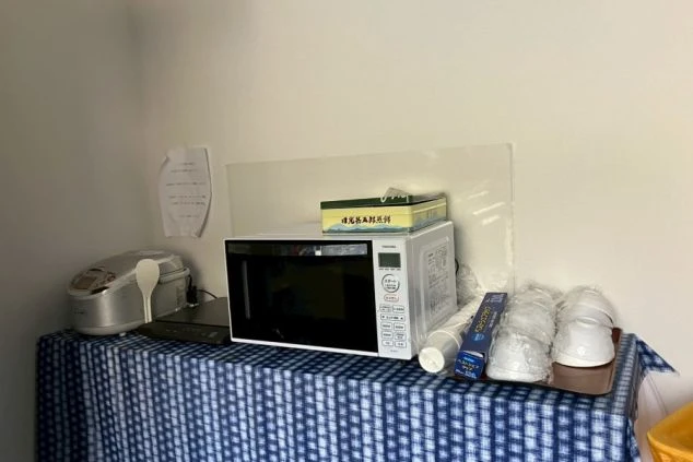 寮の共用シャワールームの入り口。ドアを開けた先にシャワー室があり、手前には脱衣所の床に白いカゴが置かれている。