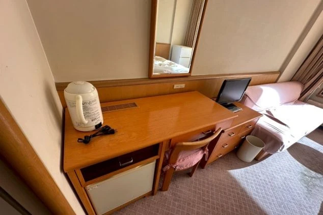 備え付けのデスク、テレビ、電気ケトル、冷蔵庫。研修やプライベートに便利な寮の設備の画像。