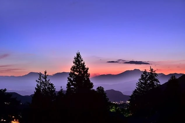 リゾートバイトの休日に観光するイメージ画像。山々のシルエットと、ピンクや紫に染まる夕焼け空の美しい風景。