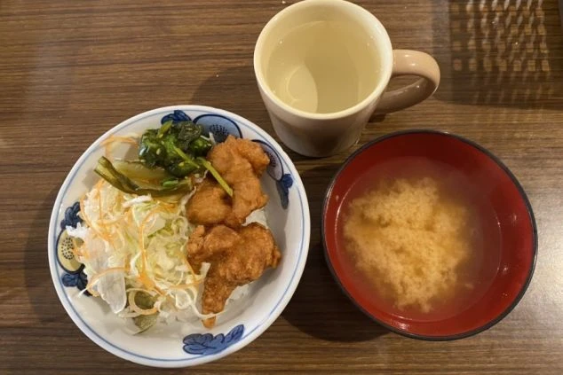 まかないを表現するイメージ画像。唐揚げと千切りキャベツがのったご飯、味噌汁、飲み物が写っている。