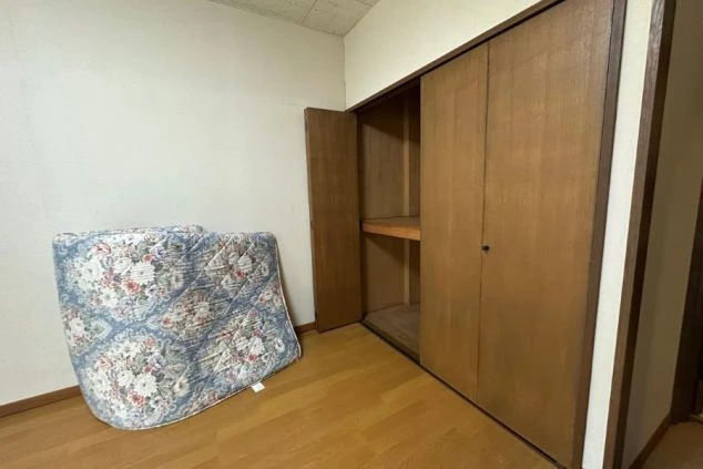 寮の個室。立てかけられたマットレスと、収納棚付きのクローゼットが映る。