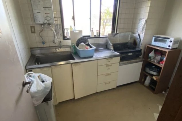 寮のキッチン。シンク、コンロ、給湯器、トースター、窓が映る共用スペース。