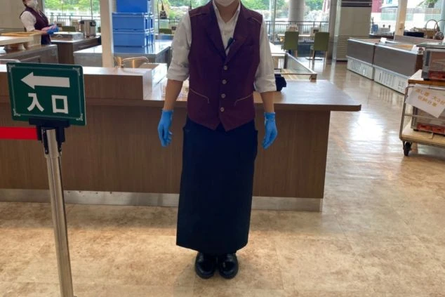 リゾートホテルのレストランで働くスタッフの制服。白いシャツとワインレッドのベスト、黒いロングエプロンを着用した、清潔感と品のあるスタイルです。リゾートバイトでは、こうした職場で働くことができます。