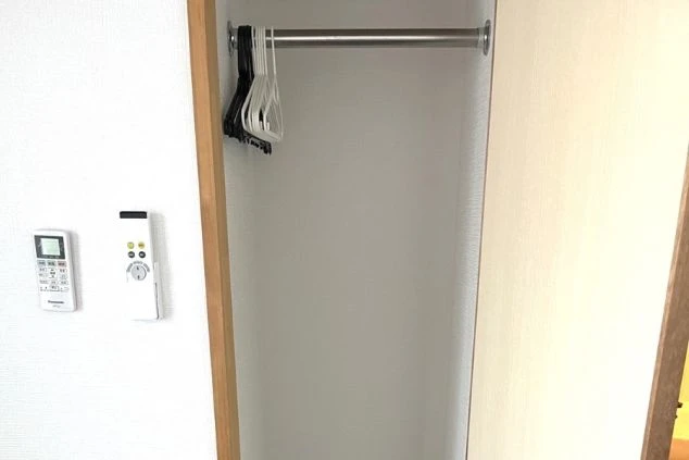 リゾートバイトの寮のクローゼットの内部の画像。ハンガーをかけるバーと複数のハンガーが備え付け。