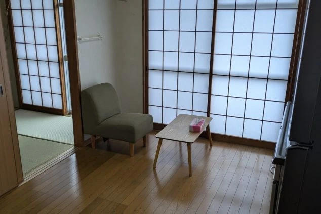 リゾートバイトの寮のリビングスペース。フローリングの部屋に、椅子とテーブルが置かれたくつろぎの空間です。