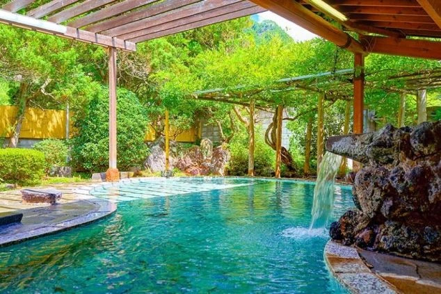 緑豊かな木々に囲まれた露天風呂の画像。リゾートバイトの仕事終わりに温泉で疲れを癒すイメージ。