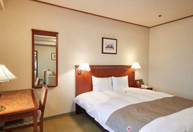 リゾートバイトの社員寮の部屋を表現するイメージ画像。ベッドや机、鏡が備え付けられたシンプルな洋室。