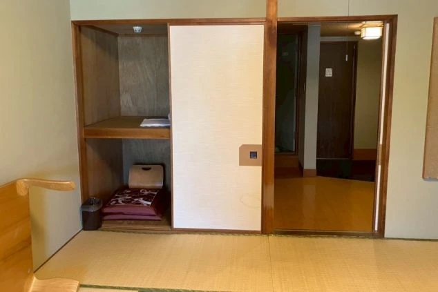 リゾートバイトの寮の部屋の中を撮影した画像。部屋の奥には収納スペースと、鏡がついた扉が見える。奥の扉は廊下につながっており、寮の部屋の全貌がわかる。リゾートバイトの寮の部屋の画像。