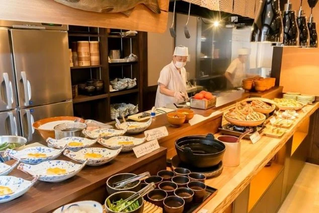 バイキング形式のレストランのライブキッチンの画像。手前にはたくさんの料理が並んでおり、奥ではシェフが調理している。リゾートバイトの仕事内容を表す、ホテルのダイニングの画像。