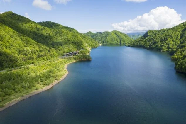 北海道定山渓にある札幌湖の風景の画像。青々とした山々と、澄んだ湖の水面が美しいコントラストをなしている。リゾートバイトの休日に観光を楽しめる、自然の風景の画像。