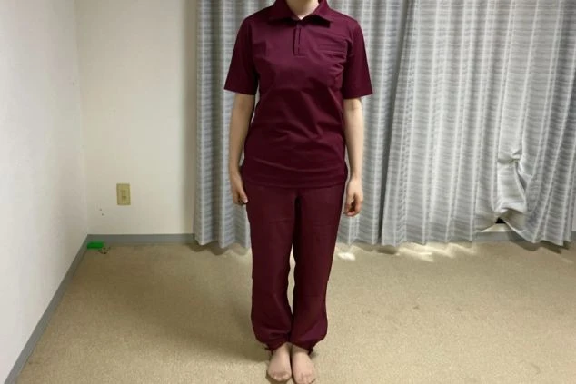 リゾートバイトで着用する制服の見本。バーガンディ色のポロシャツとパンツを着用した女性の姿。清潔感があり、動きやすそうな服装で、リゾートバイトの仕事内容をアピール。