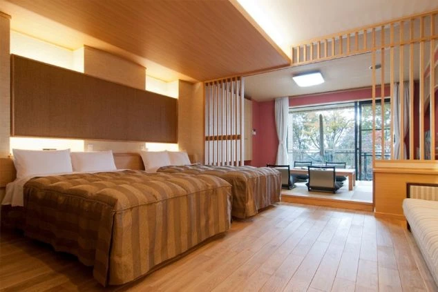 和と洋が融合した広々とした客室の画像。ツインベッドと、窓際に座卓が備わった落ち着いた空間です。