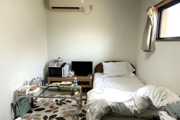 リゾートバイトの社員寮の部屋を表現するイメージ画像。ベッドとテレビ、電子レンジが置かれたシンプルな個室。