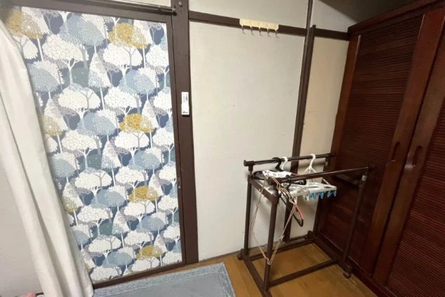 リゾートバイトの社員寮の部屋を表現するイメージ画像。洗濯物干しと木のタンスが写っている。