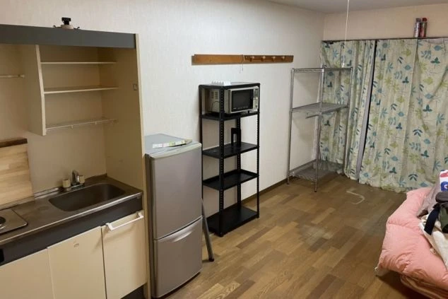 リゾートバイトの寮の部屋のクローゼットや収納棚、キッチンが一体となったスペースの画像。冷蔵庫や電子レンジ、収納ラックが備え付けられており、生活に必要な設備が整っている。リゾートバイトの寮の部屋の画像。