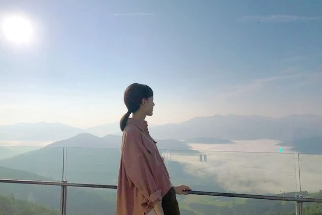 リゾートバイトの休日に観光するイメージ画像。展望台から雲海を眺めている女性の後ろ姿。