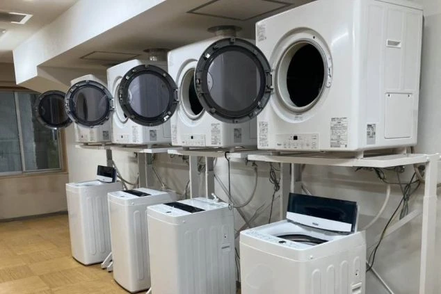 リゾートバイトの社員寮にある共用ランドリーのイメージ画像。洗濯機と乾燥機が複数台設置されている。