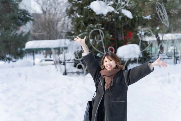 北海道定山渓にある温泉街の風景の画像。緑豊かな山々に囲まれ、渓谷には川が流れている。川にかかる赤い橋や、山間に建つホテルが見える、リゾート地の風景の画像。