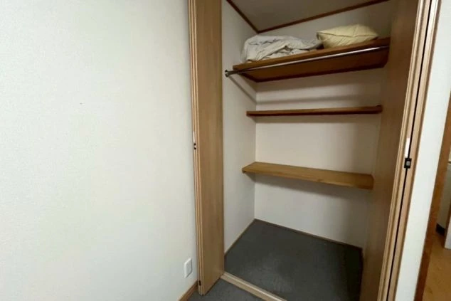 リゾートバイトの個室寮にある収納スペース。棚とハンガーポールが設置されており、荷物を整理整頓できる設備の画像。
