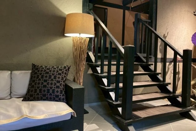 旅館のモダンな共用スペース。間接照明と木製の階段がある、おしゃれな内装の施設で働く仕事募集。