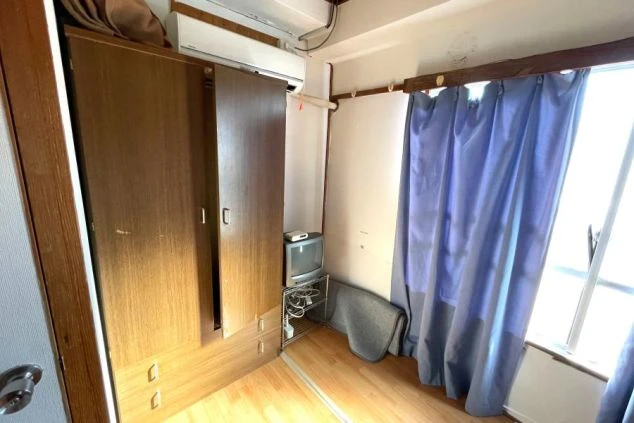 ワクトリでリゾートバイトをするスタッフが撮影した、静岡県下田でのリゾートバイトの寮の画像。タンスがあり、青いカーテンがかかっている。