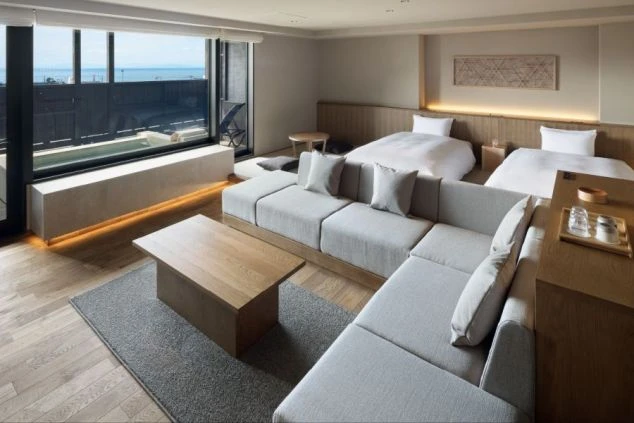 オーシャンビューのリゾートホテルの客室の画像。ベッドとソファが置かれた広々とした部屋で、窓の外には海が広がっている。