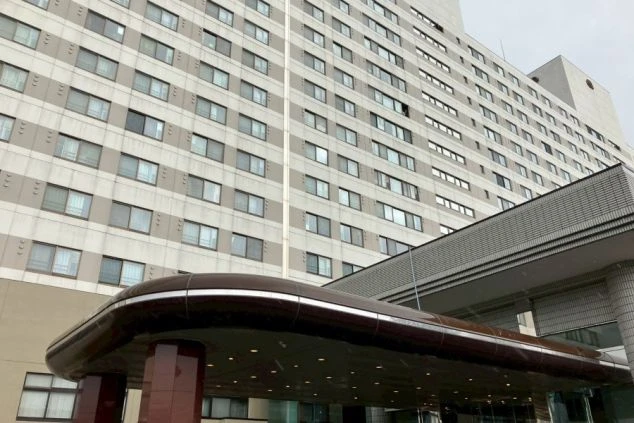 入口。モダンなデザインの庇と、ガラス張りの自動ドア、赤い大理石のような柱。