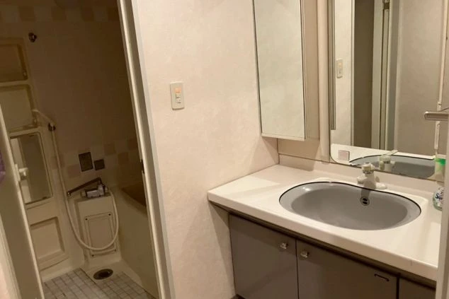 リゾートバイトの寮にある洗面所。鏡付きの独立した洗面台と、奥にはシャワー室が見える。清潔感のある設備をアピール。