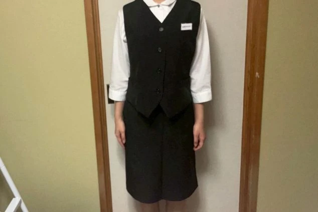白い長袖シャツに黒いベストとスカートを着用した女性スタッフの画像。レストランやホテルのダイニング、宴会場でのリゾートバイトの接客スタッフの制服画像。